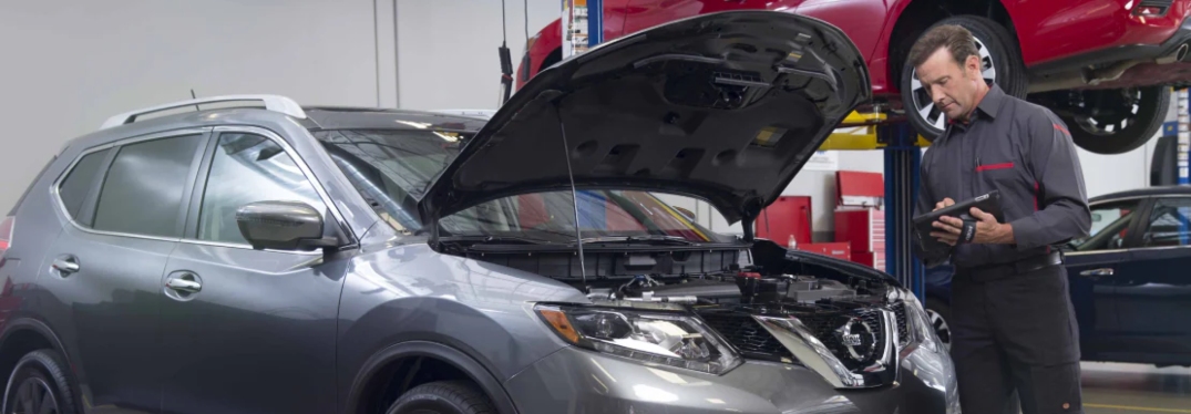 Kia Service Technician Looking Under Hood of Vehicle