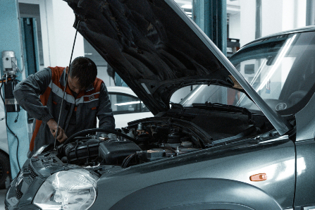 mechanic working on car with hood up 