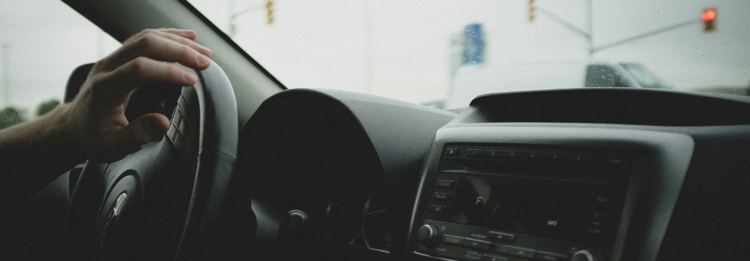 View of Car Dash with Hand on Wheel